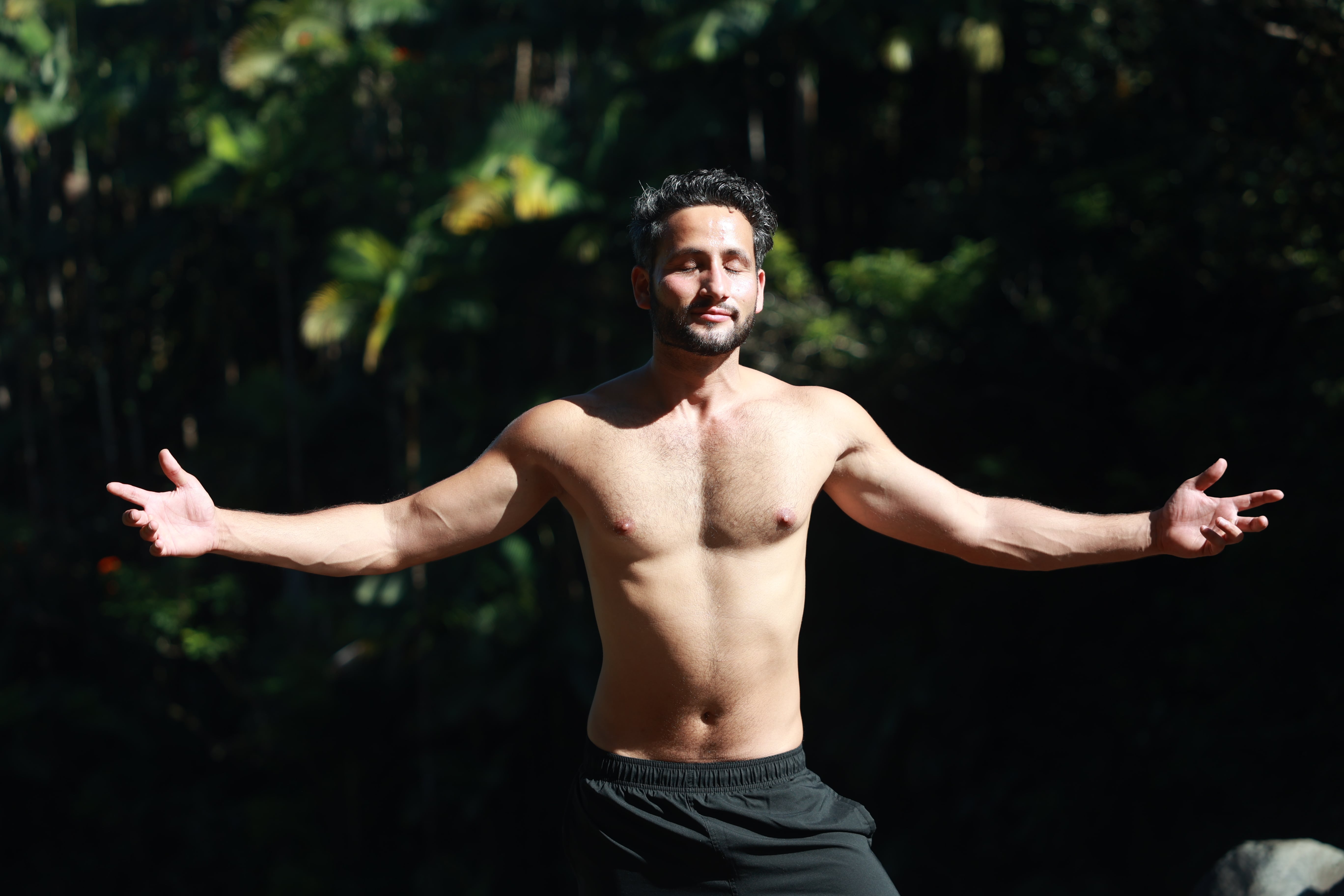 Sunny Binjola standing with arms open in nature — men's transformational coach
